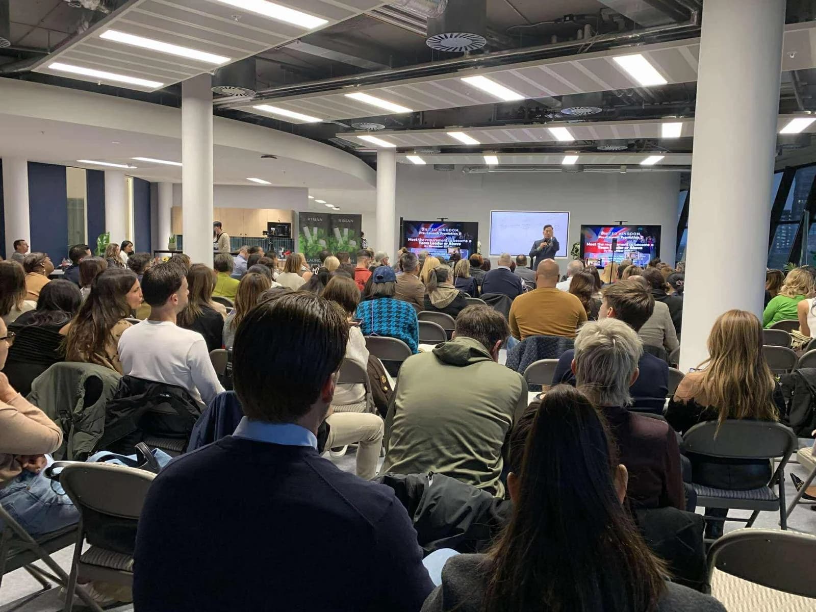 Pubblico seduto rivolto verso una presentazione.